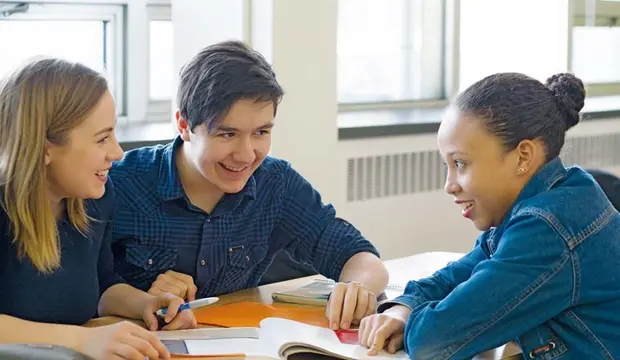 Trois jeunes rient en étudiant ensemble